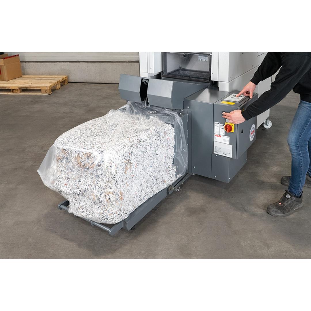 Combinaison destructeur-presse à balles P4 Coupe croisée Forte capacité SP 5080 Powerline 3,9 x 40 mm HSM - Opérateur sortant une balle de papier compressé de la presse de la combinaison HSM Powerline SP 5080